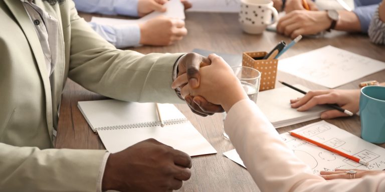 Man and woman shaking hands at table. Unity concept